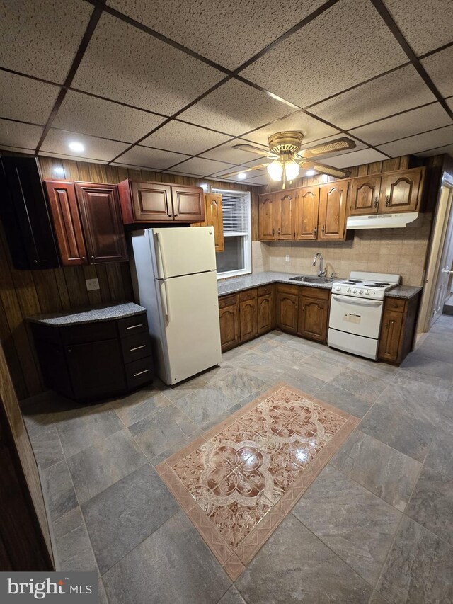 kitchen featuring a sink, light countertops, under cabinet range hood, a drop ceiling, and white appliances