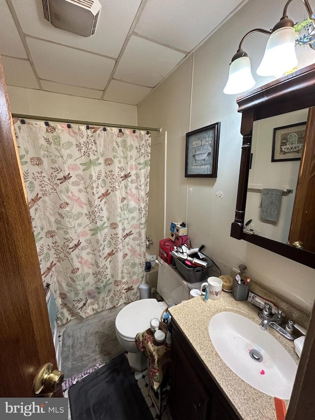 bathroom with shower / tub combo, visible vents, a drop ceiling, toilet, and vanity