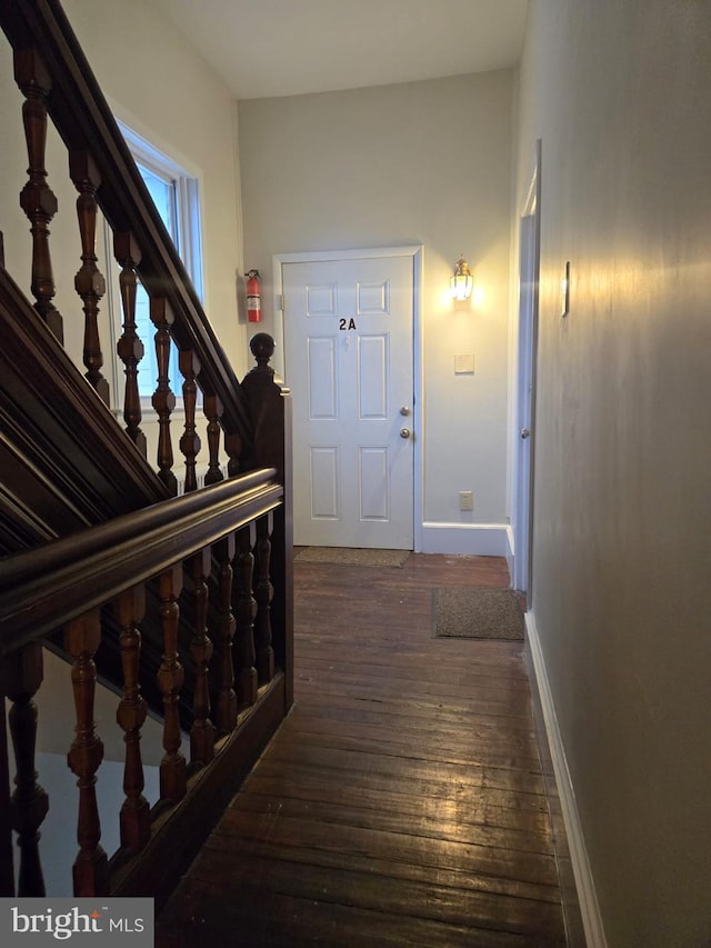 interior space featuring dark wood finished floors, baseboards, and stairs