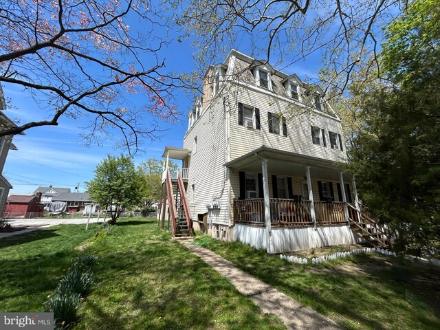 view of property exterior featuring a porch, a lawn, stairway, and mansard roof