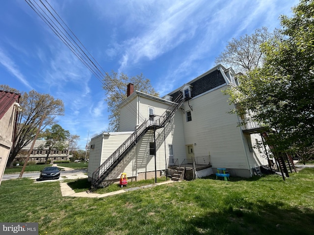 rear view of property with a lawn, a chimney, and mansard roof
