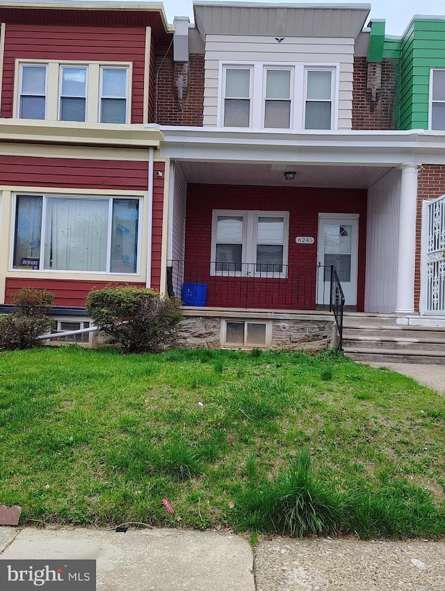 view of front of property featuring a porch, a front lawn, and brick siding