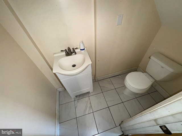 half bath with vanity, marble finish floor, and toilet