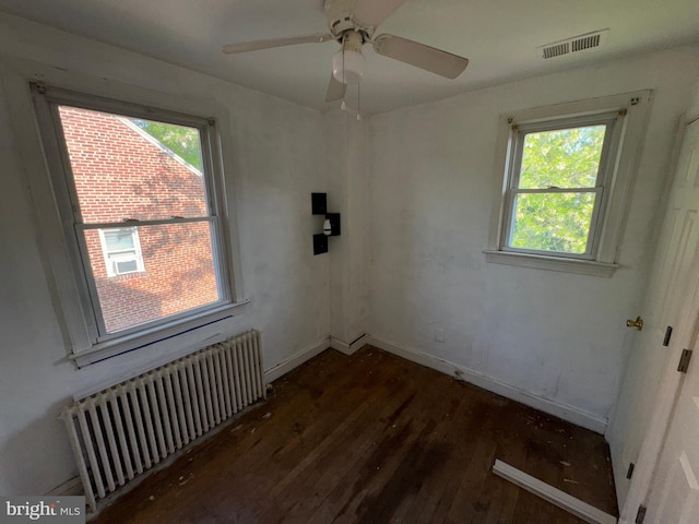unfurnished room with visible vents, baseboards, radiator heating unit, and hardwood / wood-style floors