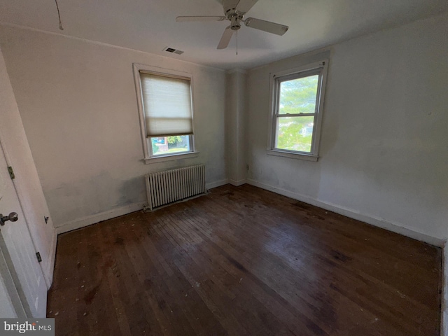 spare room featuring visible vents, plenty of natural light, radiator heating unit, and wood finished floors