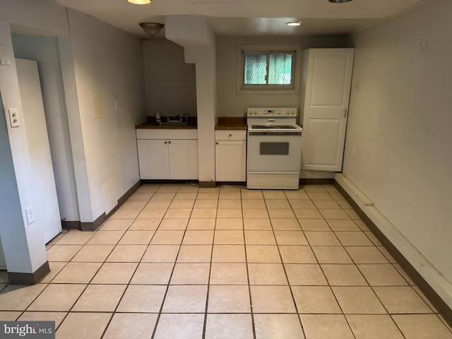 kitchen featuring dark countertops, a sink, electric stove, white cabinetry, and baseboards
