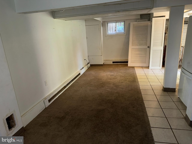 below grade area featuring visible vents, freestanding refrigerator, light carpet, baseboards, and light tile patterned floors