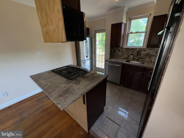 kitchen with crown molding, a peninsula, tasteful backsplash, a sink, and stainless steel appliances