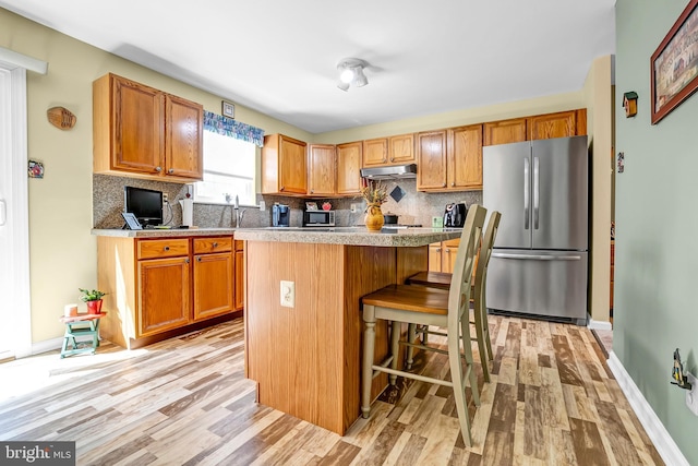 kitchen featuring stainless steel appliances, light wood finished floors, tasteful backsplash, and a center island