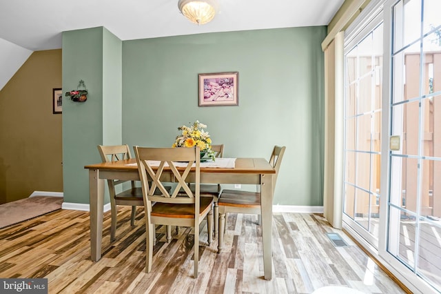 dining room featuring wood finished floors, baseboards, and healthy amount of natural light