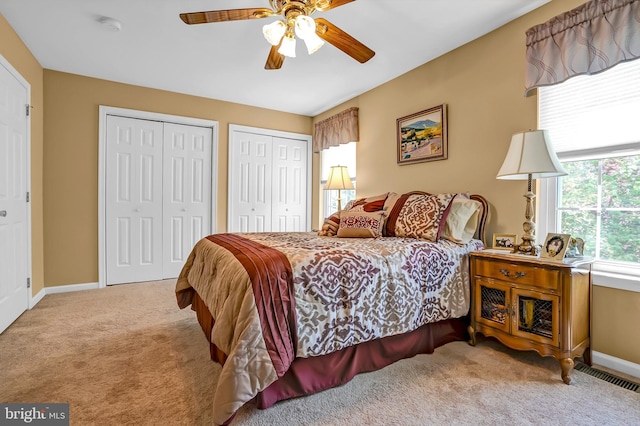 carpeted bedroom with multiple closets, baseboards, and a ceiling fan