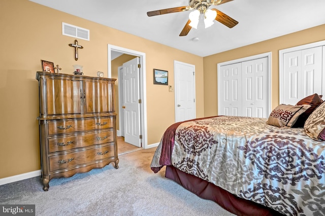 bedroom with light colored carpet, baseboards, two closets, and a ceiling fan