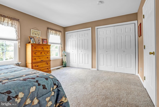 bedroom with multiple closets, carpet floors, and baseboards