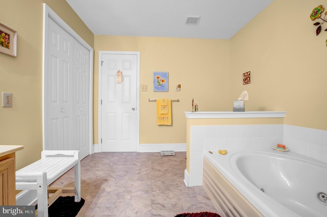 bathroom featuring a jetted tub, vanity, and baseboards
