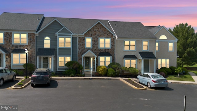 view of property featuring uncovered parking and stone siding