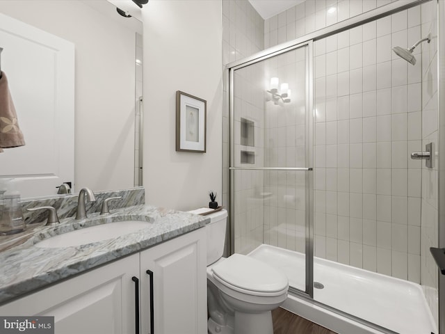 bathroom with vanity, a shower stall, toilet, and wood finished floors