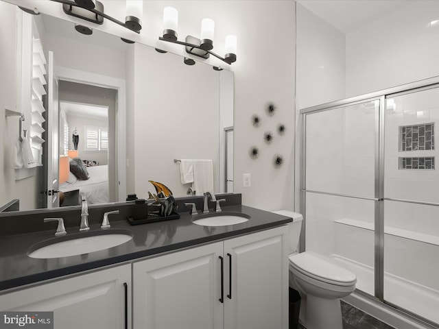ensuite bathroom with a shower with shower door, double vanity, a sink, and ensuite bathroom