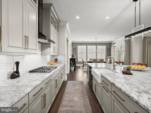 kitchen featuring a sink, dark wood finished floors, wall chimney exhaust hood, stainless steel gas stovetop, and ornamental molding