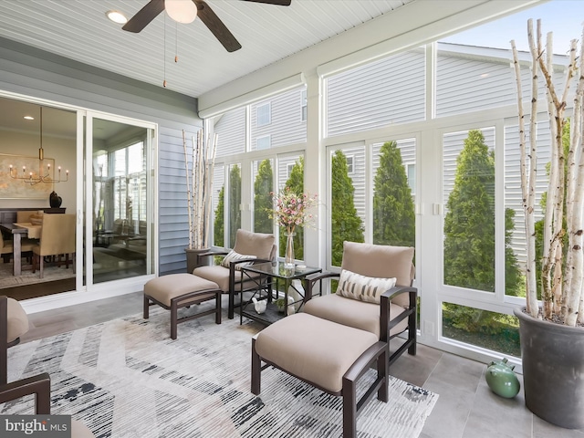 sunroom / solarium featuring ceiling fan with notable chandelier