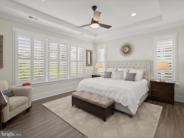 bedroom with visible vents, dark wood finished floors, baseboards, a tray ceiling, and recessed lighting
