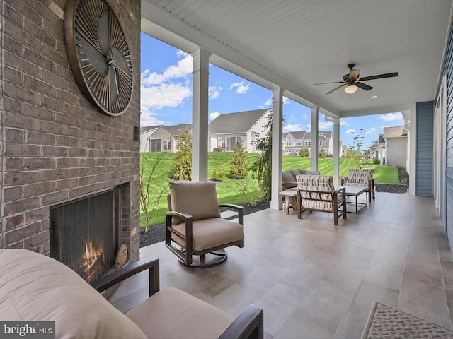 view of patio featuring a ceiling fan, an outdoor living space with a fireplace, and a residential view