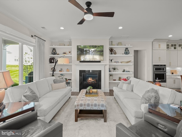 living room featuring a glass covered fireplace, ornamental molding, a ceiling fan, and recessed lighting