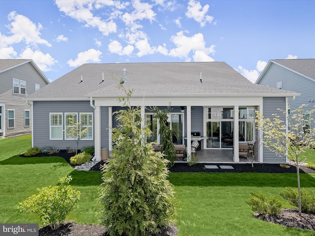 back of house featuring roof with shingles, a patio, and a yard