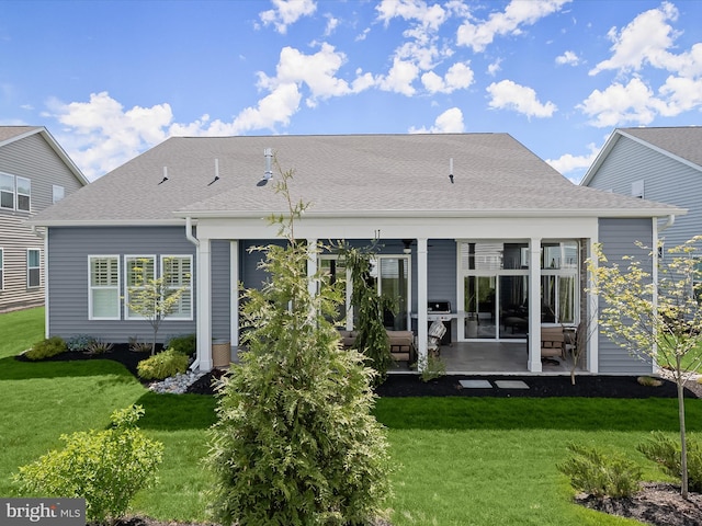 back of house with a lawn, a patio, and roof with shingles