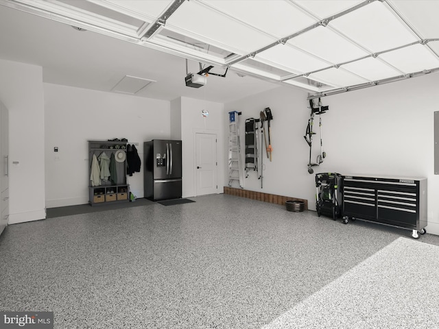 garage with a garage door opener and stainless steel fridge with ice dispenser