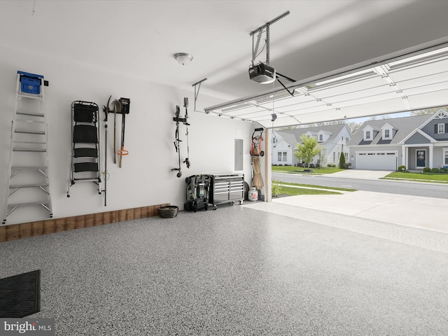 garage featuring a residential view, visible vents, a garage door opener, and electric panel