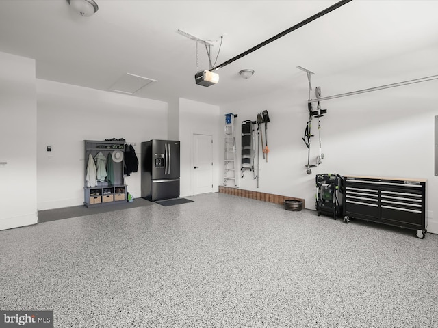garage featuring baseboards, a garage door opener, and black fridge