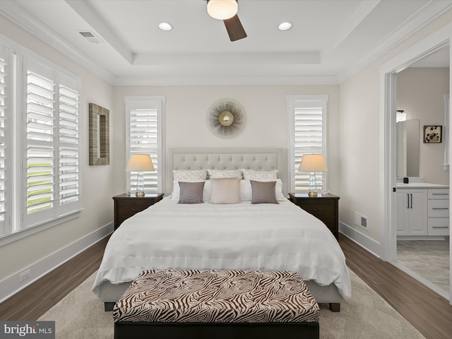 bedroom featuring visible vents, wood finished floors, and a tray ceiling