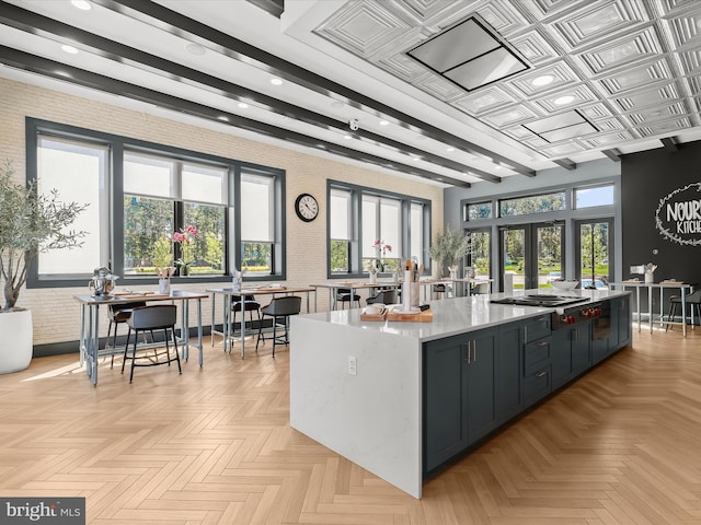 kitchen featuring beam ceiling, brick wall, a large island, light countertops, and french doors
