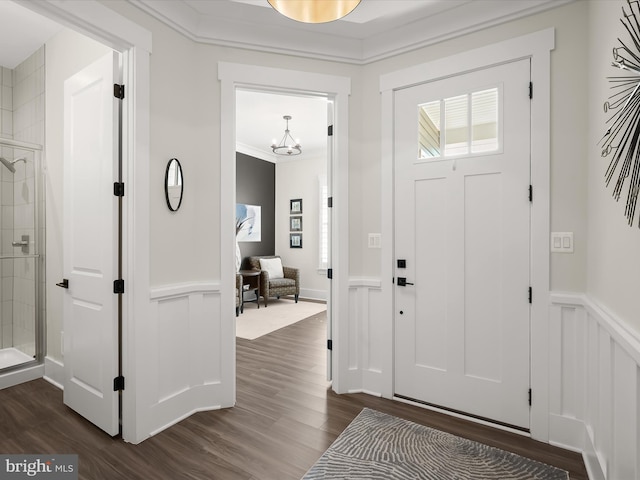 foyer with a decorative wall, wainscoting, dark wood finished floors, and a chandelier