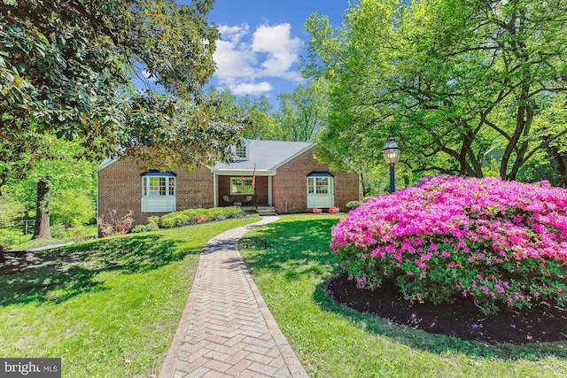 view of front facade featuring brick siding, covered porch, and a front yard