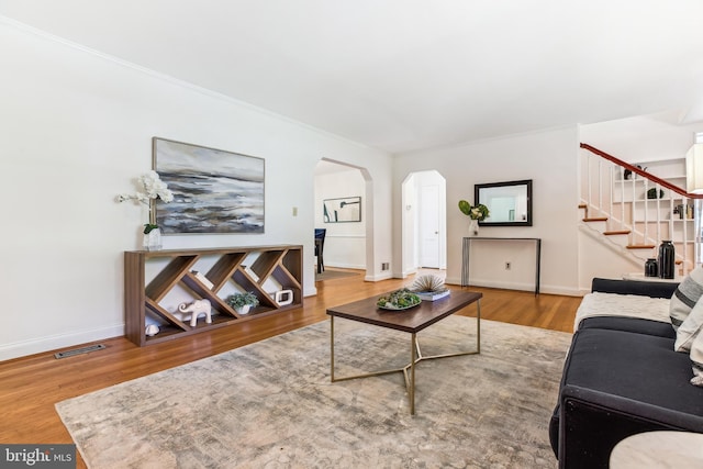 living room featuring visible vents, arched walkways, stairs, and baseboards