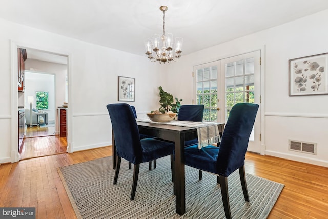 dining area featuring visible vents, light wood-style flooring, a chandelier, and a wealth of natural light