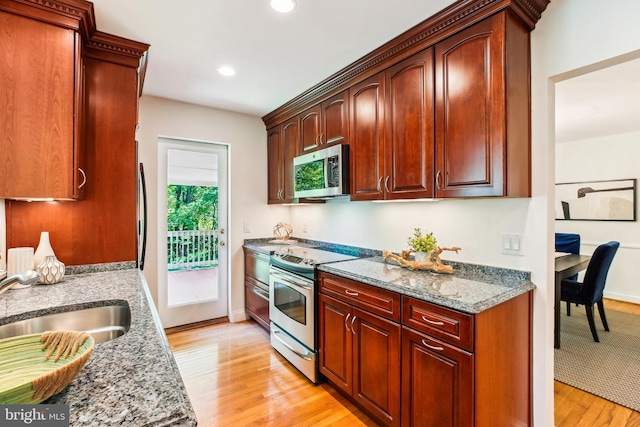 kitchen featuring light wood-type flooring, recessed lighting, light stone counters, a sink, and stainless steel appliances