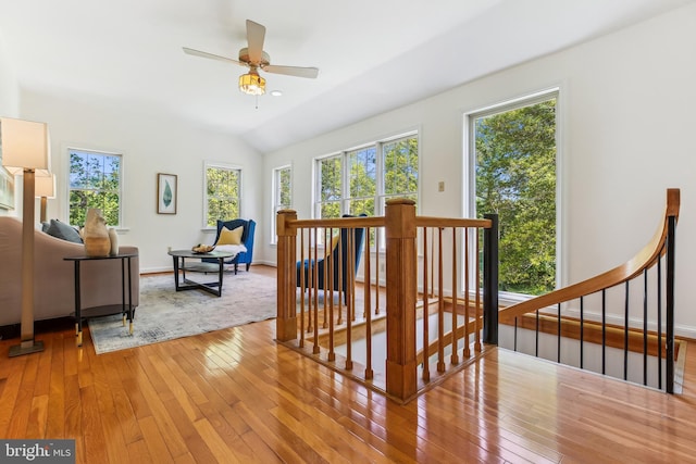 living room with light wood-style floors, baseboards, ceiling fan, and vaulted ceiling