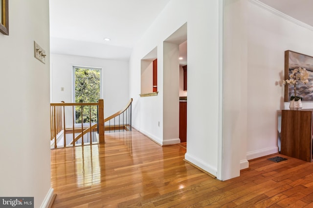 corridor featuring light wood-style floors, recessed lighting, baseboards, and an upstairs landing