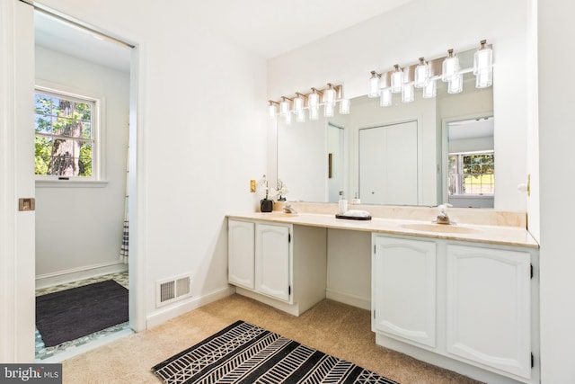 bathroom with visible vents, a sink, a healthy amount of sunlight, and double vanity