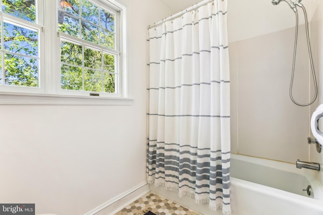 bathroom featuring baseboards and shower / bathtub combination with curtain