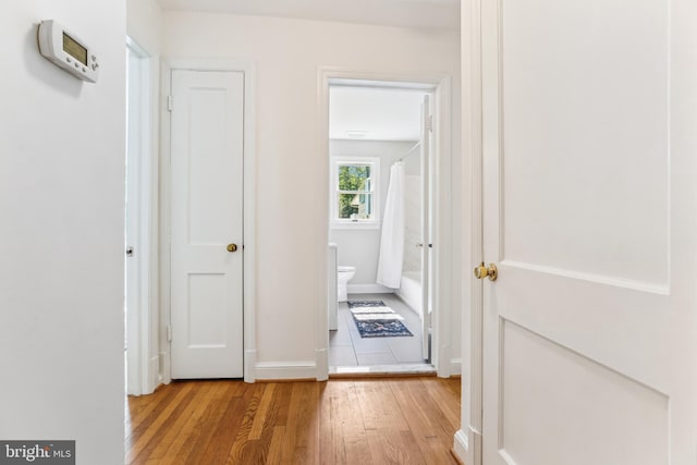 hallway featuring light wood-style floors and baseboards