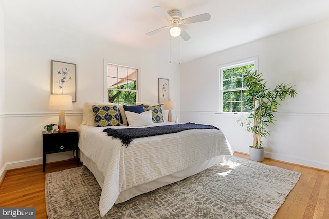 bedroom with a ceiling fan, baseboards, and wood finished floors