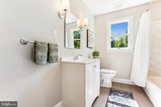 bathroom featuring toilet, baseboards, plenty of natural light, and wood finished floors