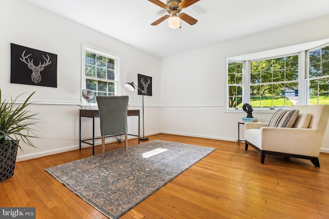 living area featuring baseboards, ceiling fan, and hardwood / wood-style floors