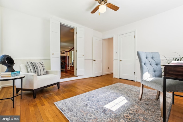 living area with stairway, ceiling fan, and wood-type flooring