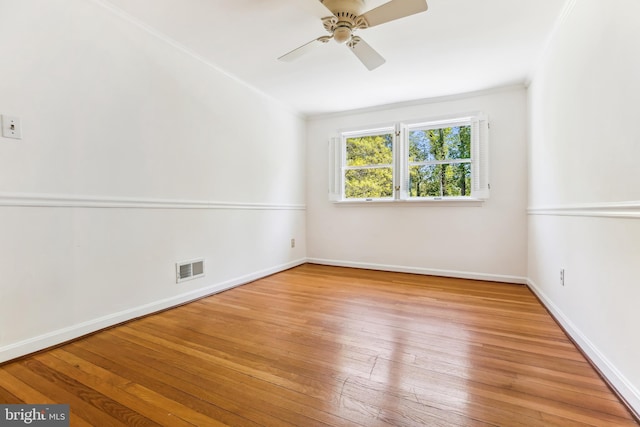 spare room with wood-type flooring, baseboards, visible vents, and ceiling fan