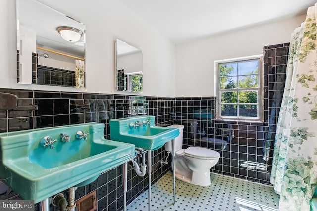 full bathroom featuring tile walls, a sink, a wainscoted wall, toilet, and a shower with shower curtain