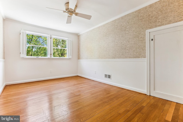 unfurnished room with a ceiling fan, visible vents, baseboards, ornamental molding, and hardwood / wood-style floors